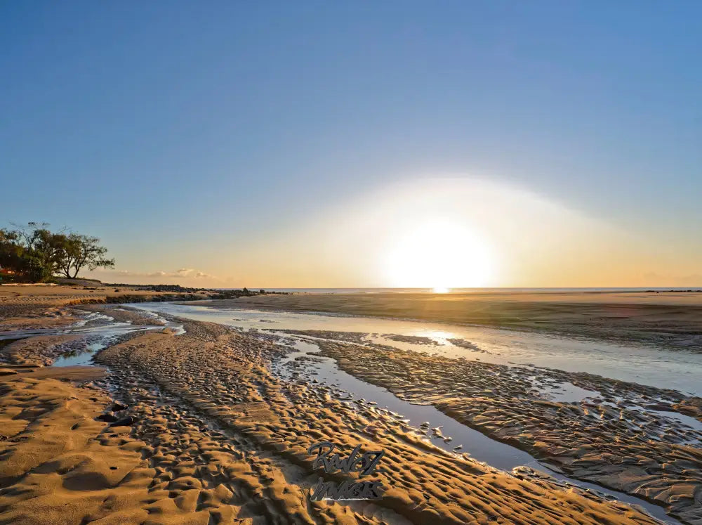 Bright sunrise over tidal creek bed with golden sand patterns Queensland