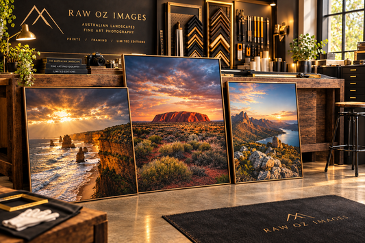 Three framed Australian landscape prints, including Uluru and coastal cliffs, in a Raw Oz Images framing workshop.
