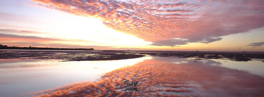 Red dawn sunrise reflection on wet sand at low tide Golden Beach panoramic