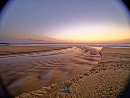 Fisheye view of pre-dawn light reflecting on glassy calm beach water