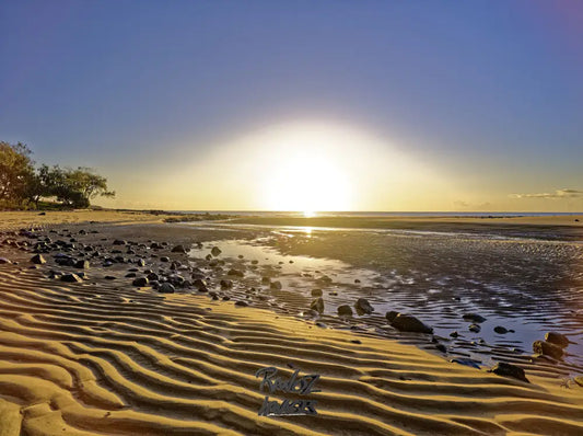 Sunrise light spilling over water rocks and sand Australian beach texture